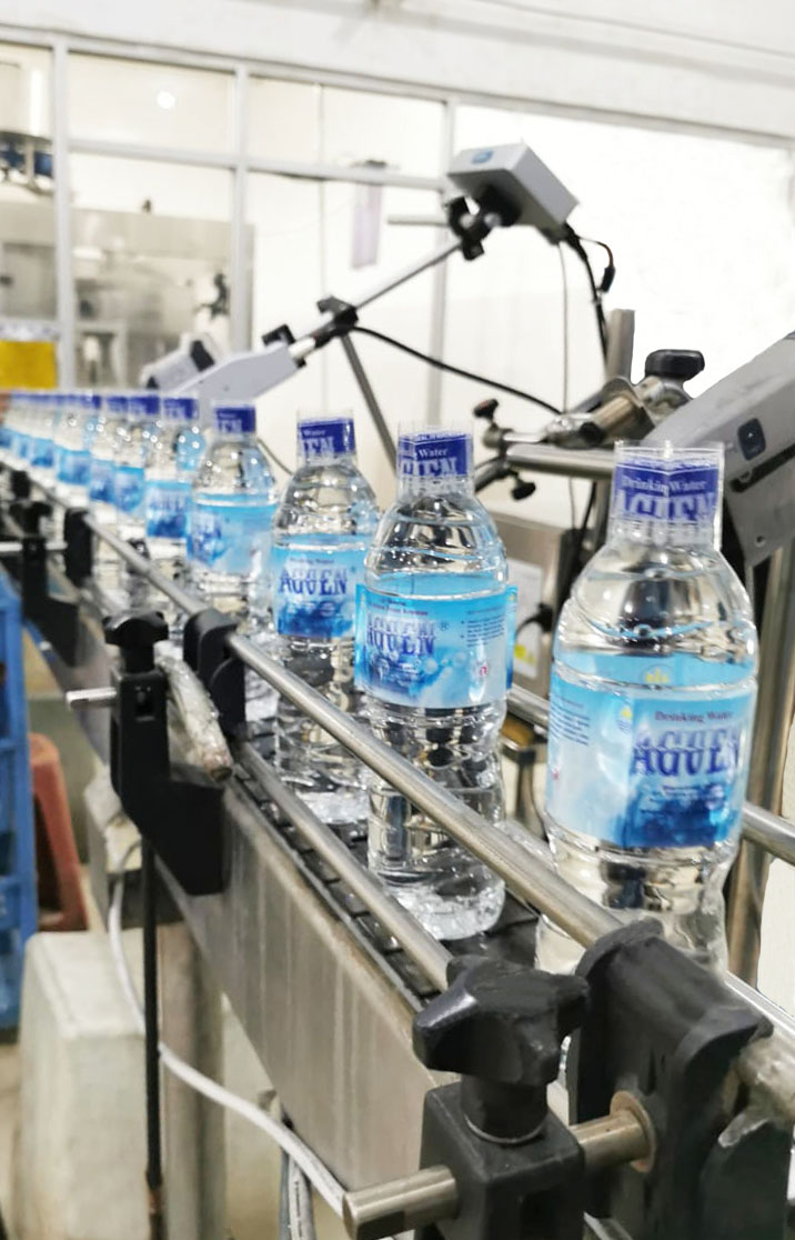 Lini produksi AGUEN — botol air minum pada conveyor belt